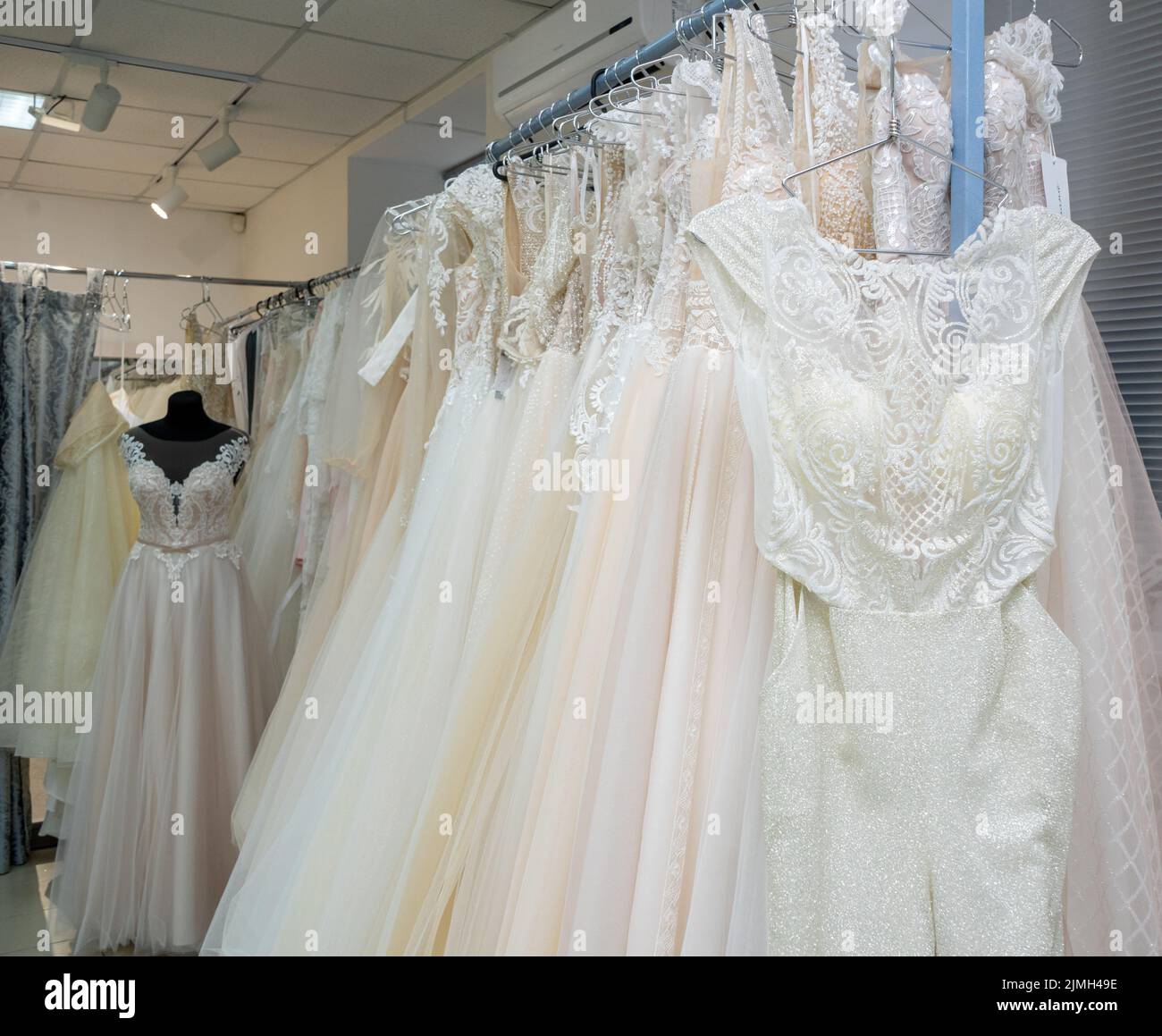 White and cream wedding dresses on a hanger in a bridal boutique Stock Photo