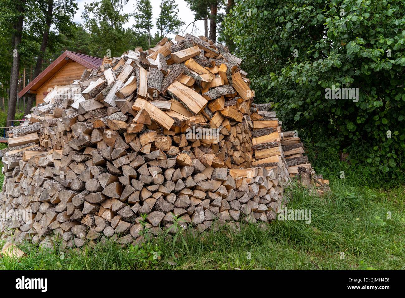 chopped firewood stacked in a woodpile in the yard of the house Stock