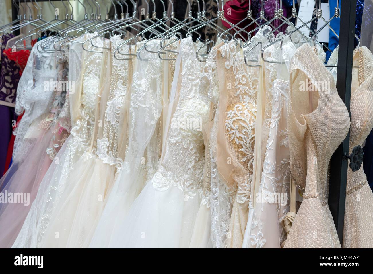 White and cream wedding dresses on a hanger in a bridal boutique. Close up Stock Photo