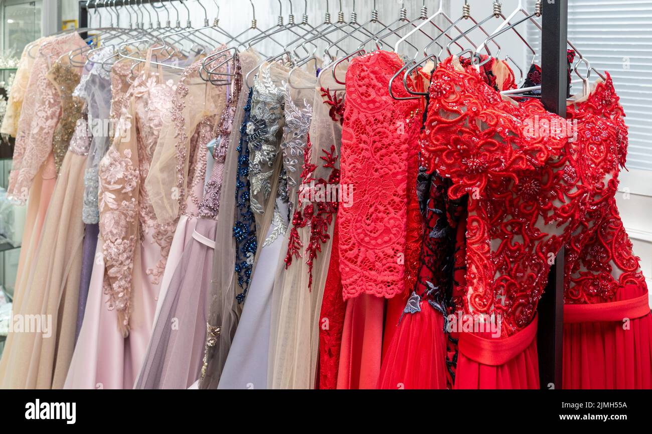 Multicolored wedding and evening dresses on a rack in a bridal shop Stock Photo