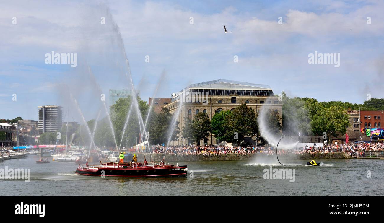 Crowds along Bristol harbour quayside on hot summer day watching historic fire-float, Pyronaut, and fly boarding display during festival Stock Photo