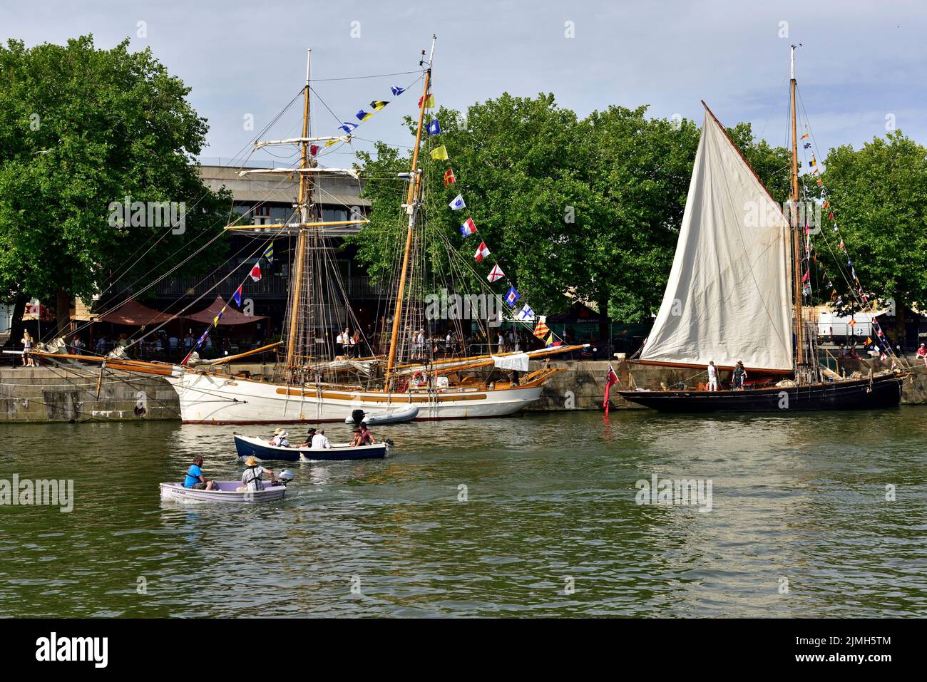 Bristol floating harbour on hot sunny day with two small boats and two tall sailing ships by quayside during festival, UK Stock Photo