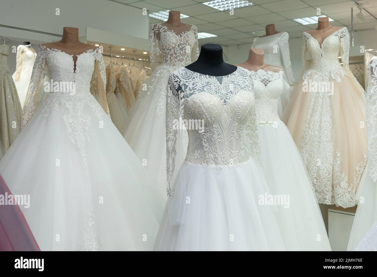 A close-up of a wedding dress against the background of other wedding dresses in a bridal salon Stock Photo