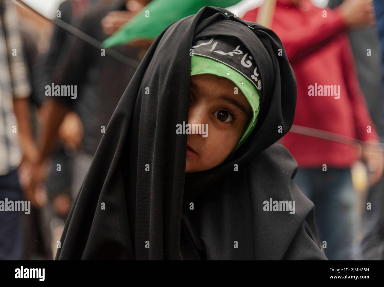 A Shia Muslim girl looks on as she participates in a procession on the 7th day of Muharram. Muharram is the first month of Islam. It is one of the holiest months on the Islamic calendar. Shia Muslims commemorate Muharram as a month of mourning in remembrance of the martyrdom of the Islamic Prophet Muhammad's grandson Imam Hussain, who was killed on Ashura (10th day of Muharram) in the battle of Karbala in 680 A.D. Stock Photo