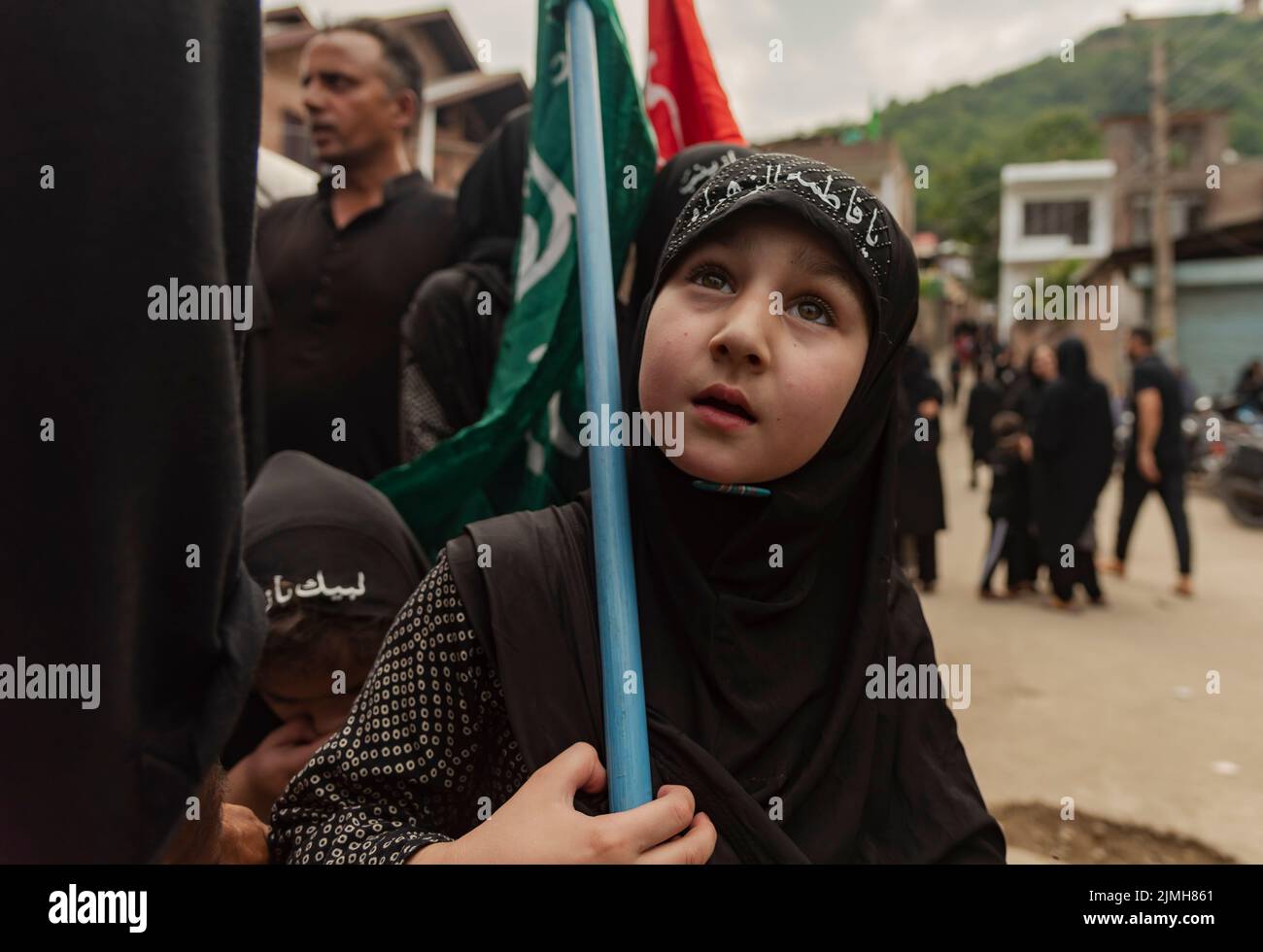 A Shia Muslim girl holds a religious flag as she participated in a religious procession on the 7th day of Muharram. Muharram is the first month of Islam. It is one of the holiest months on the Islamic calendar. Shia Muslims commemorate Muharram as a month of mourning in remembrance of the martyrdom of the Islamic Prophet Muhammad's grandson Imam Hussain, who was killed on Ashura (10th day of Muharram) in the battle of Karbala in 680 A.D. Stock Photo