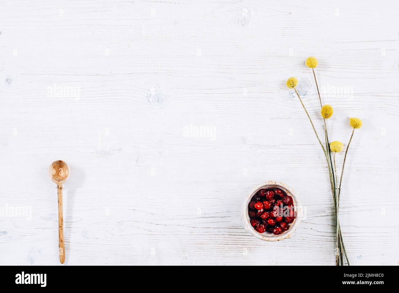 white floral background red dried berries spoon Stock Photo