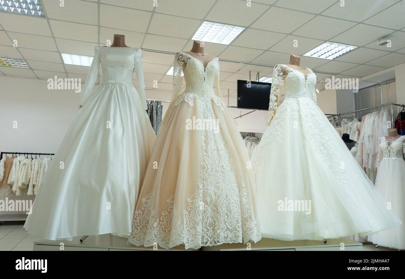 Three chic wedding dresses on mannequins. Three different models of beautiful wedding dresses. Stock Photo