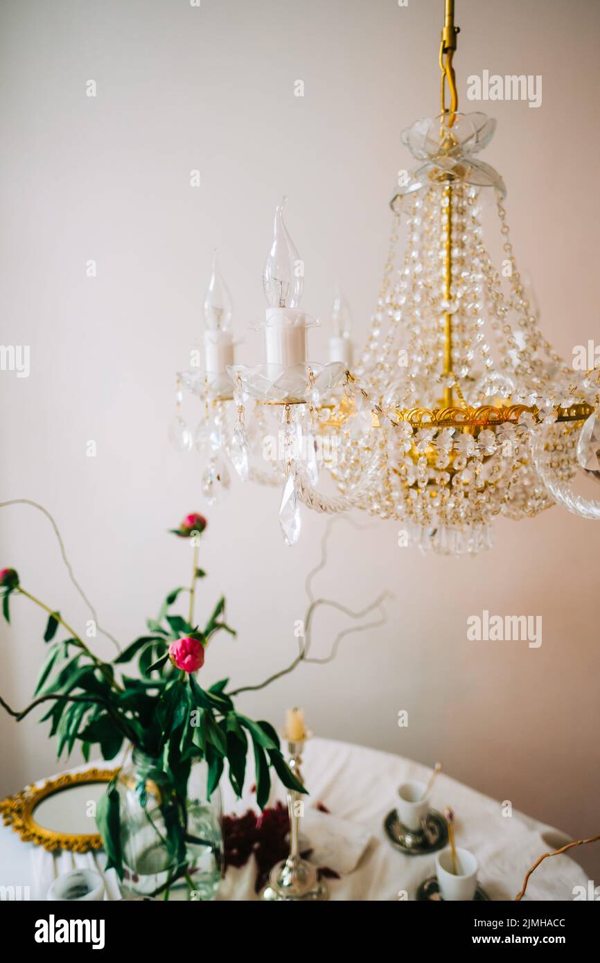 Interior of bright living room with chandelier and table with flowers ...