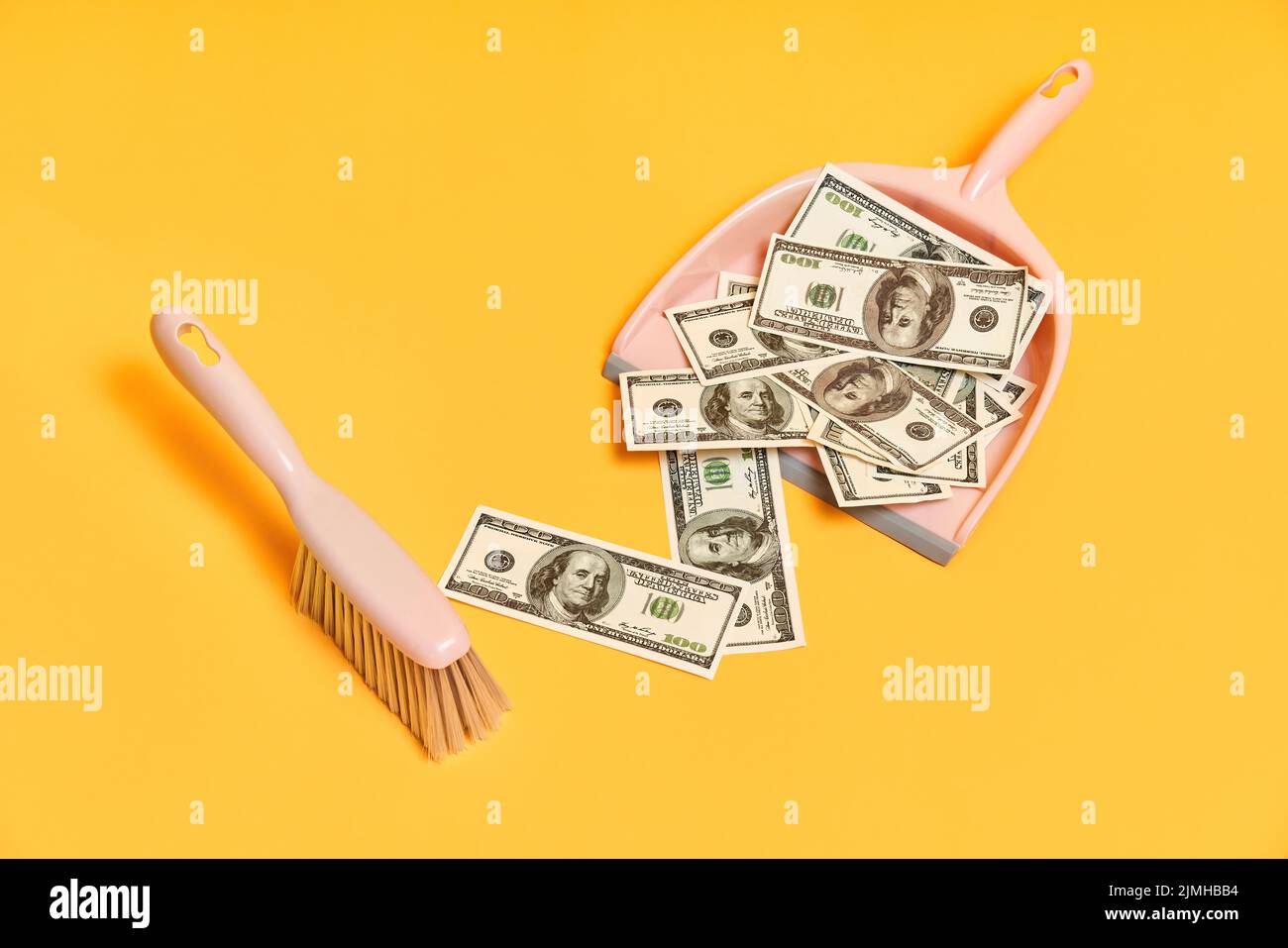 Creative layout with dustpan, hand brooms and money dollar bills on red background Stock Photo