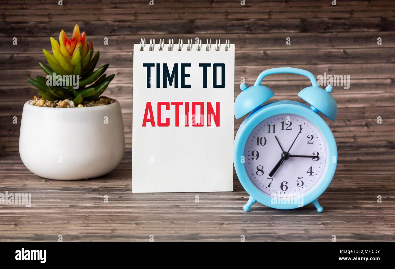 Text TIME TO ACTION text on notepad and wooden table with clock, business concept Stock Photo
