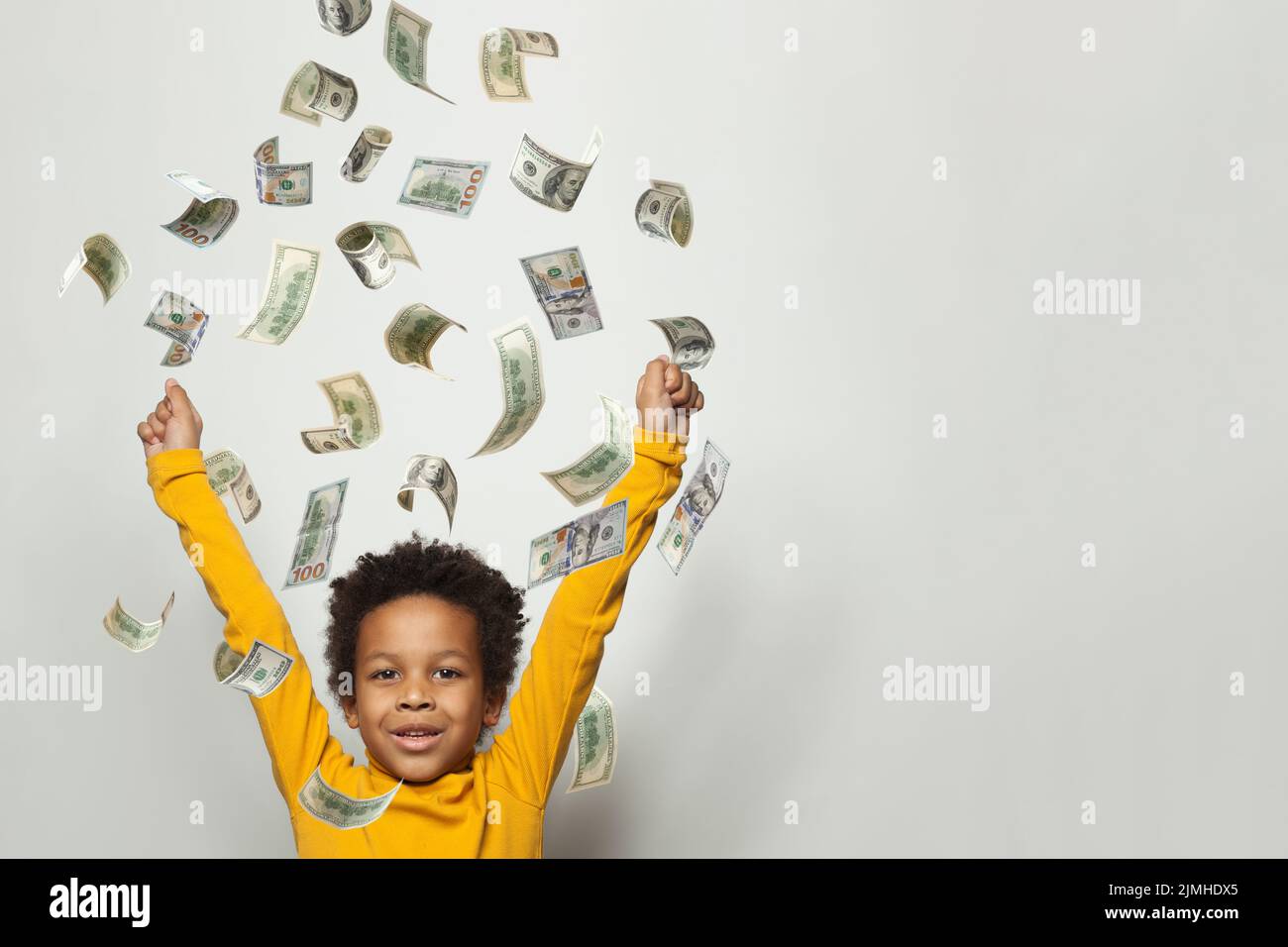 Kid screaming super excited. Happy young child celebrating success under money rain falling down dollar bills banknotes Stock Photo