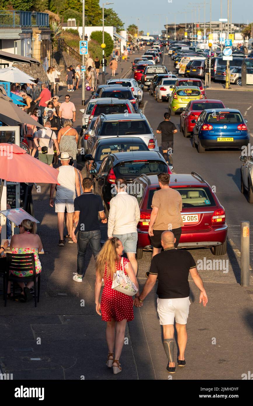 Southend on Sea, Essex, UK. 6th Aug, 2022. The sunny weather has brought people to the seaside resort, with youngsters gathering for a car meet in the evening. Traffic jam of slow moving cars passing people walking Stock Photo