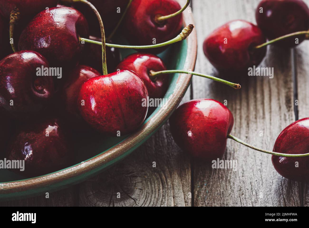 Closeup of sweet cherries in bowl on wooden table, seasonal fruit background Stock Photo