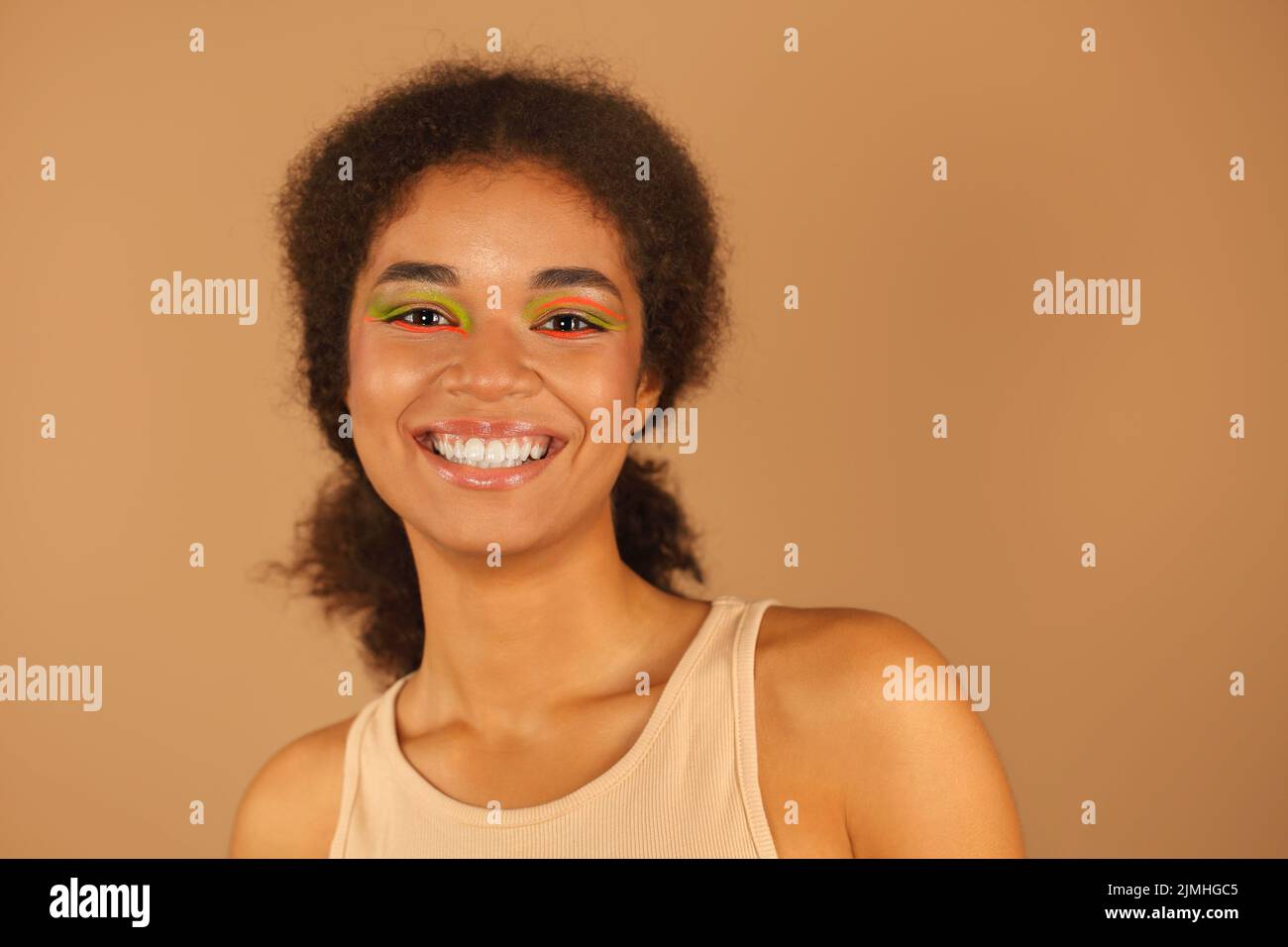 Beauty portrait of attractive young african american woman with neon color make-up smiling at camera Stock Photo