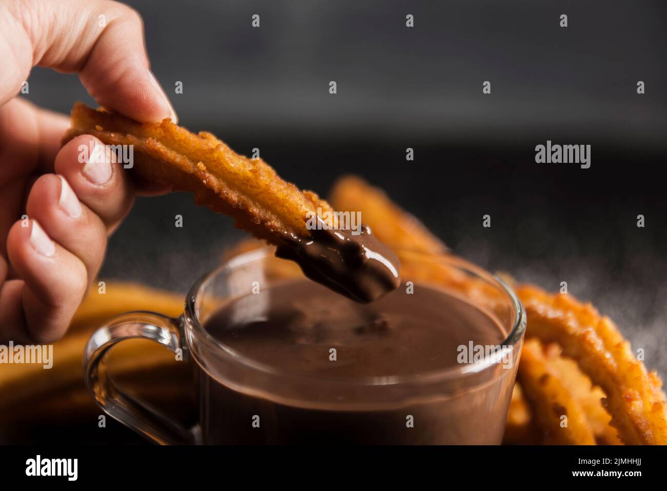 Hand dipping fried churros chocolate Stock Photo