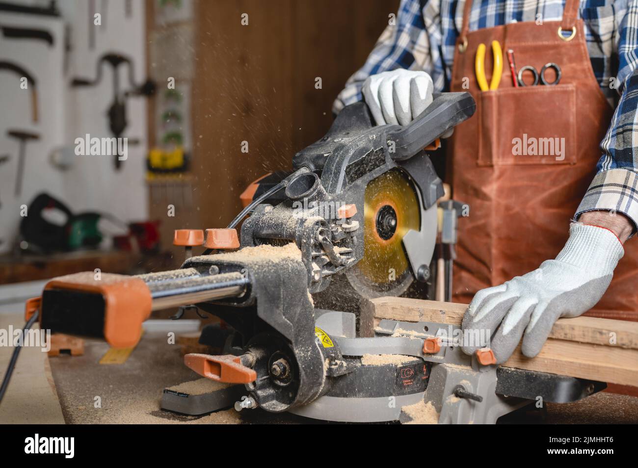 Carpenter using an electric circular saw, cutting piece of wood Stock