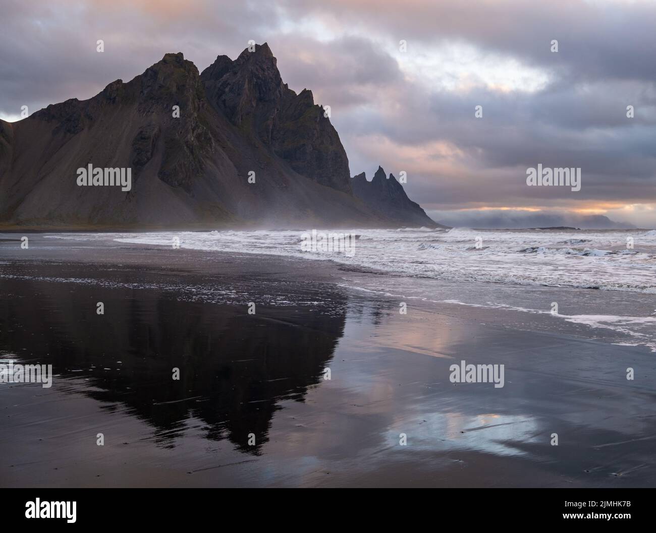 Sunrise Stokksnes cape sea beach and Vestrahorn Mountain with its reflection on wet black volcanic sand surface, Iceland. Amazin Stock Photo