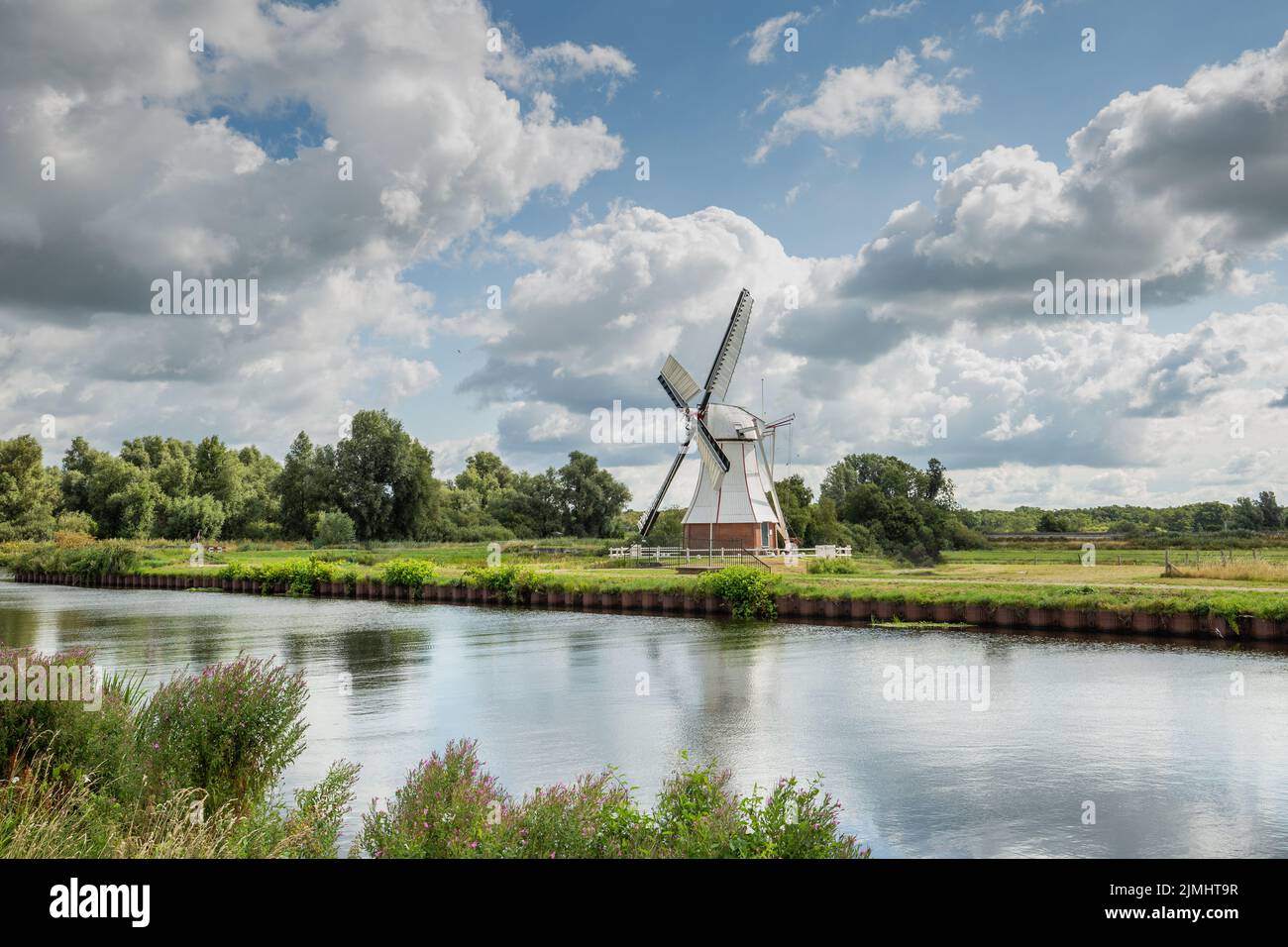 Polder landscape with canal and Witte Molen in Haren Glimmen in the Dutch province of Groningen to grind the water from the polder to the drainage sys Stock Photo