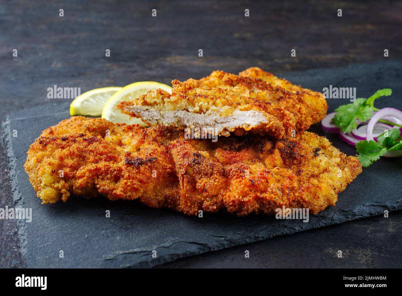 Traditional deepfried schnitzel with lemon slices and onion rings