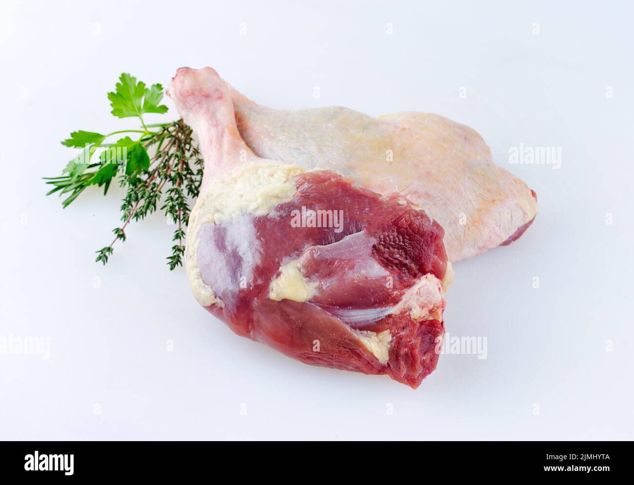 Traditional raw gourmet duck leg offered with herbs as close-up on a