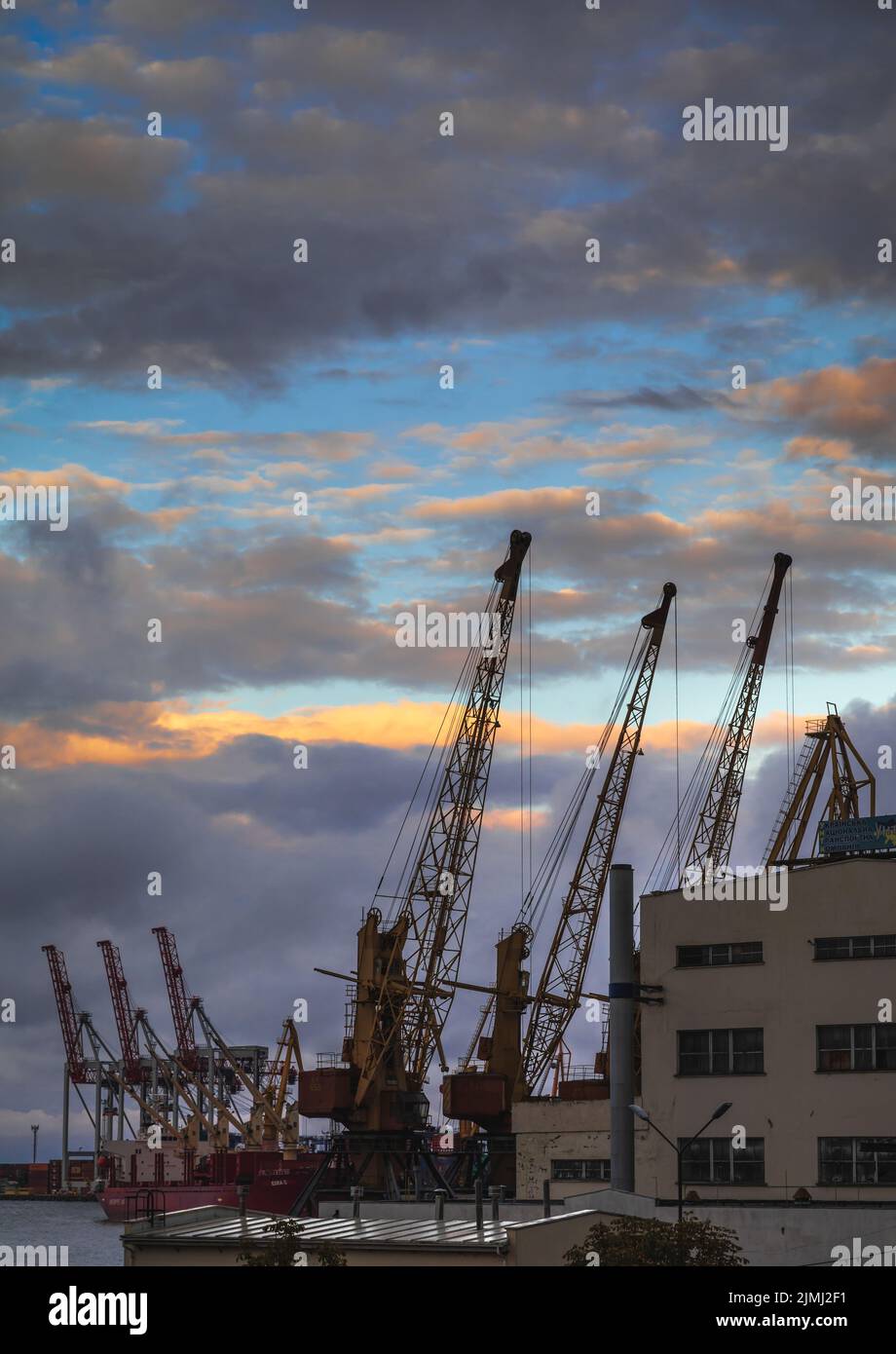 Silhouettes of loading cranes against the backdrop of sunset at the marine port in Odessa. For the first time since the beginning of the Russian war of aggression against Ukraine, a ship carrying grain has left the port of Odessa. This should make millions of tons of grain available again for the world market. Before the Russian war of aggression, Ukraine was one of the world's most important grain exporters. For them, billions in revenue from the sale of wheat and corn, among other commodities, is at stake. Stock Photo
