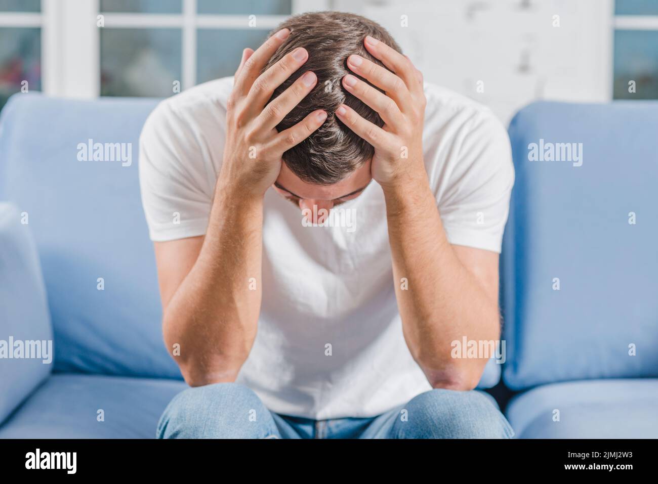 Frustrated man suffering from headache sitting sofa Stock Photo