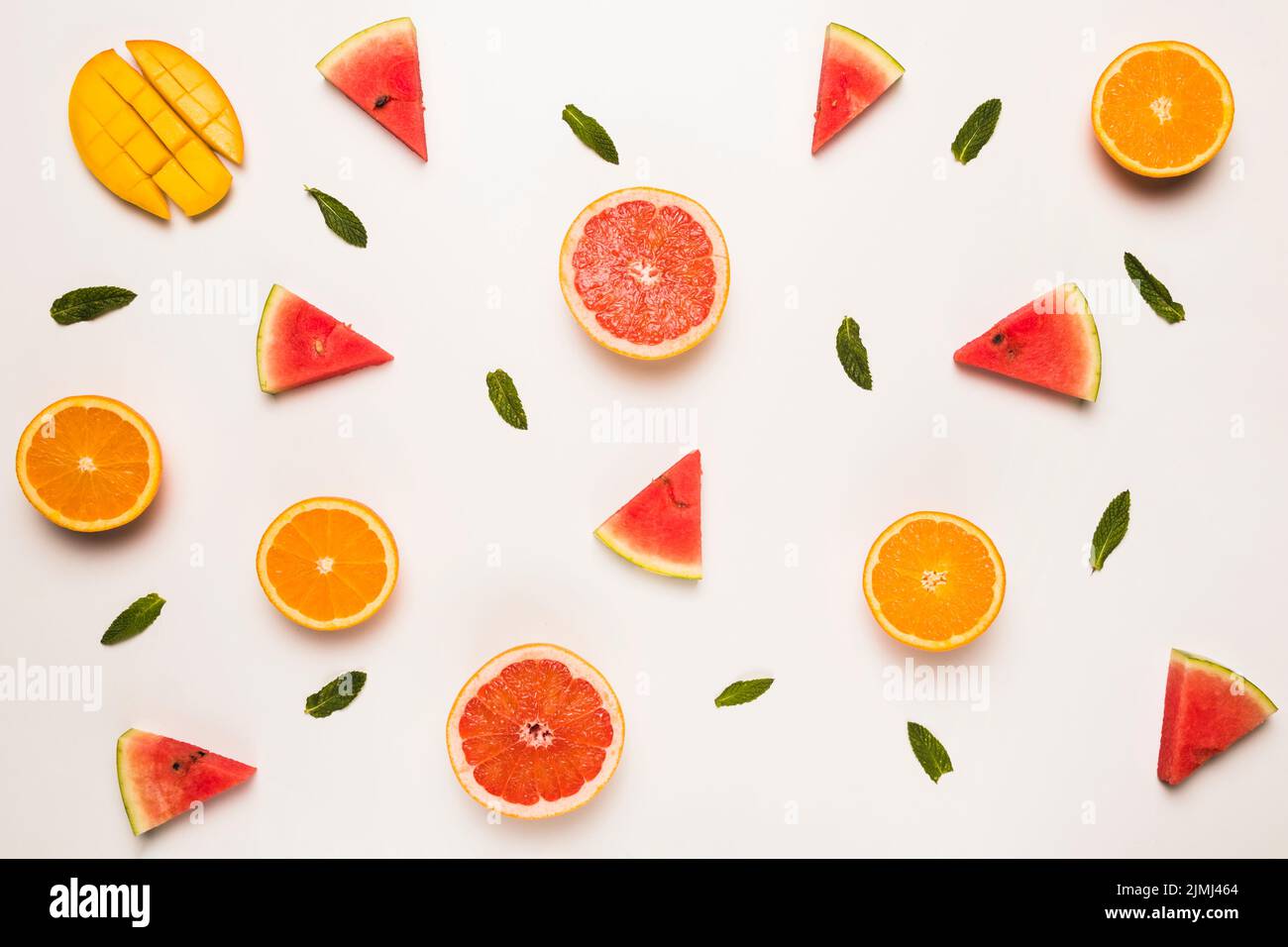 Sliced grapefruit watermelon orange mango green leaves Stock Photo