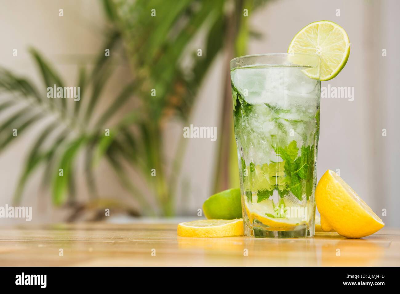 Slices fruits near glass drink with ice herbs board Stock Photo