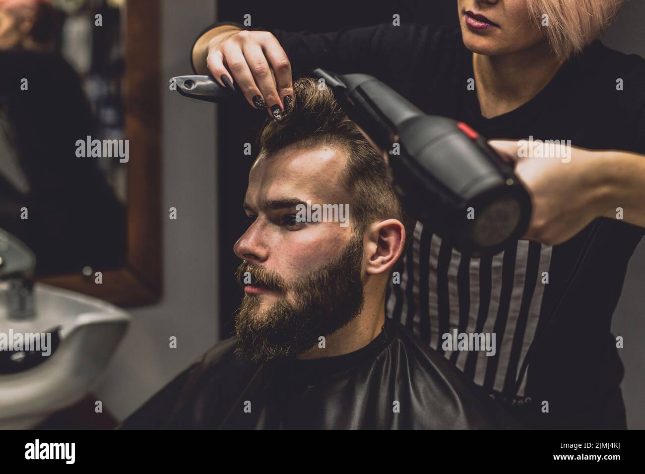 Barber woman drying hair client Stock Photo