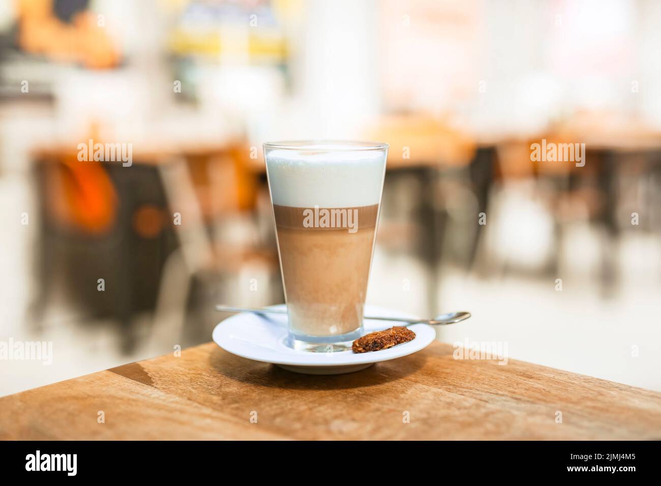 https://c8.alamy.com/comp/2JMJ4M5/cappuccino-coffee-glass-with-spoon-wooden-table-2JMJ4M5.jpg