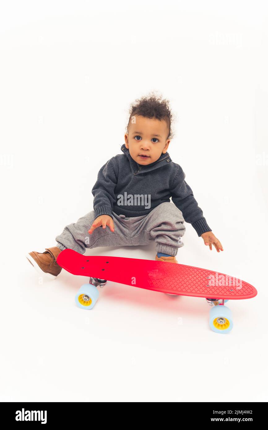 cute african american 5 years old boy sitting near the red skateboard