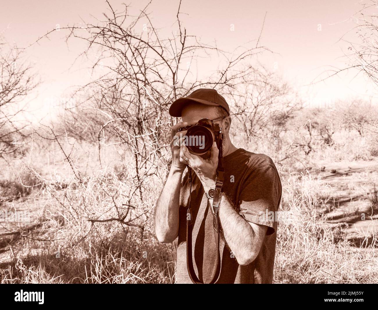 South Africa - August 21 2007: Sepia toned unrecognizable man wearing cap holding camera to his eye Stock Photo