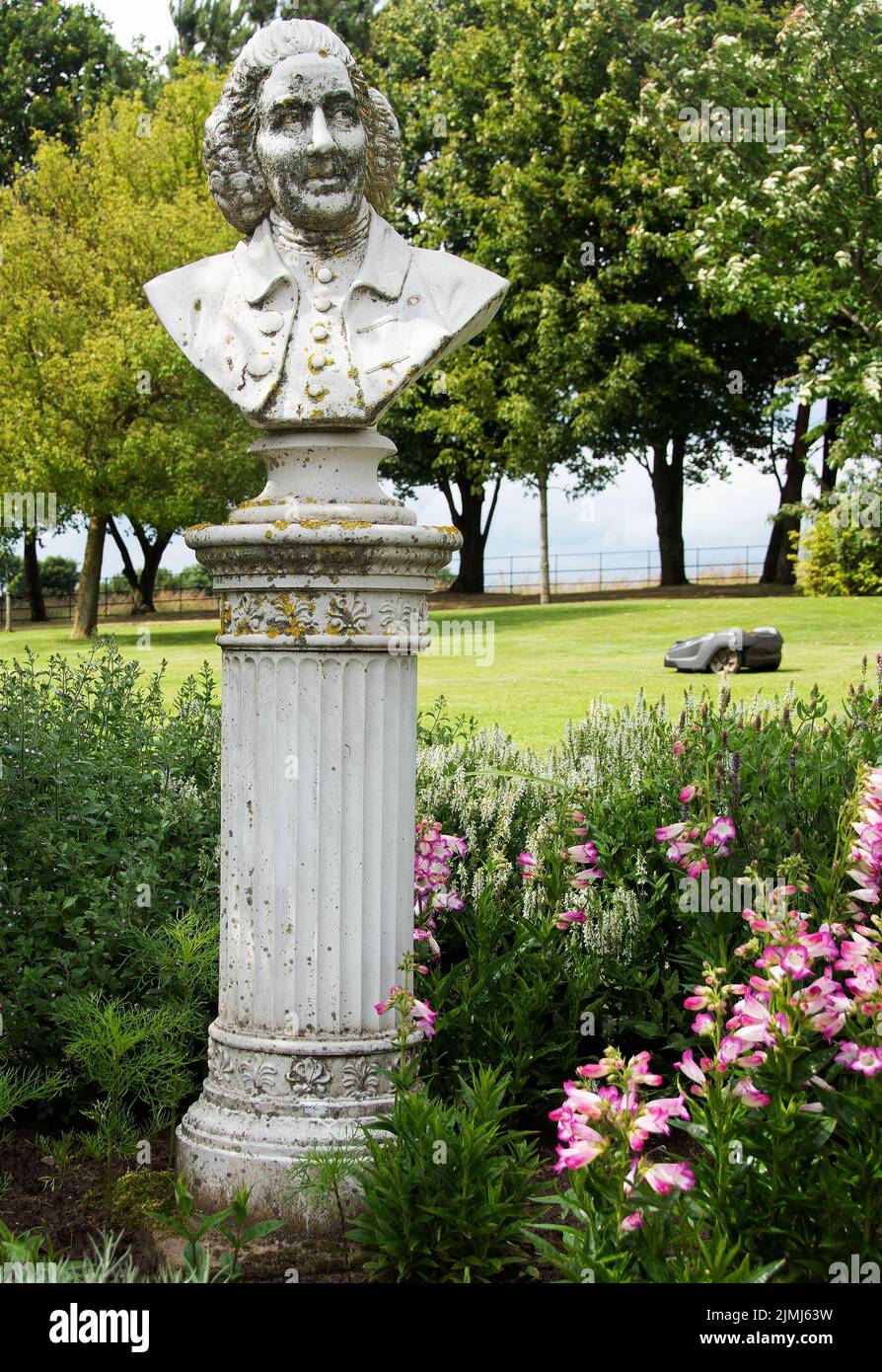 Capability Brown Bust and a robot mower at Brightwater Gardens Stock Photo