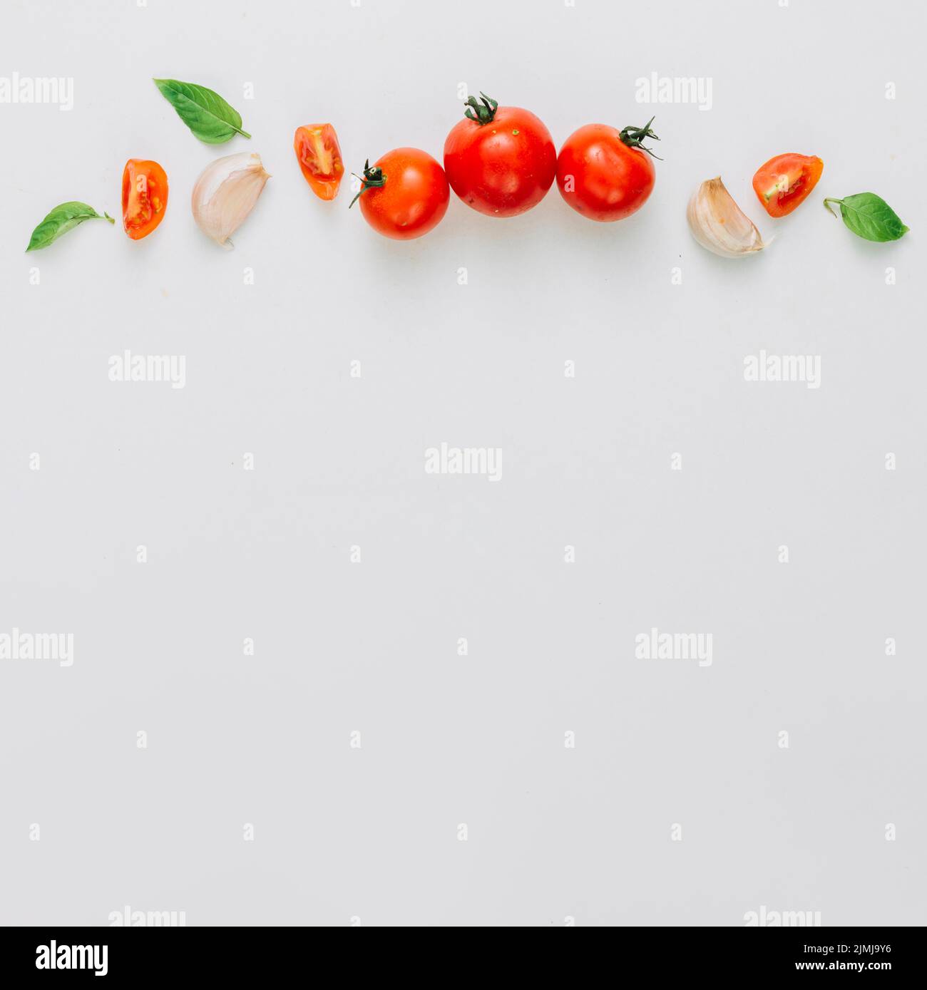 Whole slice cherry tomatoes garlic clove basil white background Stock Photo