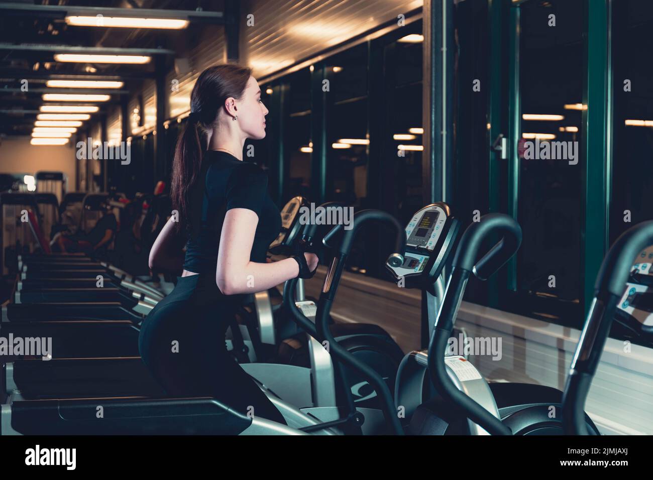 Young woman exercising elliptical cardio machine Stock Photo