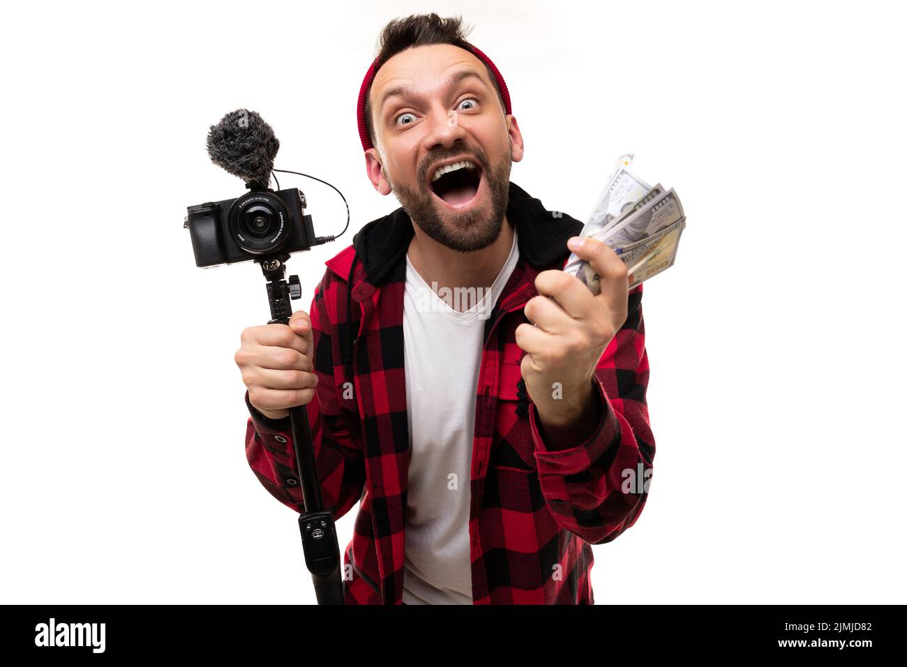 Happy blogger streamer with a camera and a wad of money in his hands laughs emotionally looking at the camera with a smile on hi Stock Photo