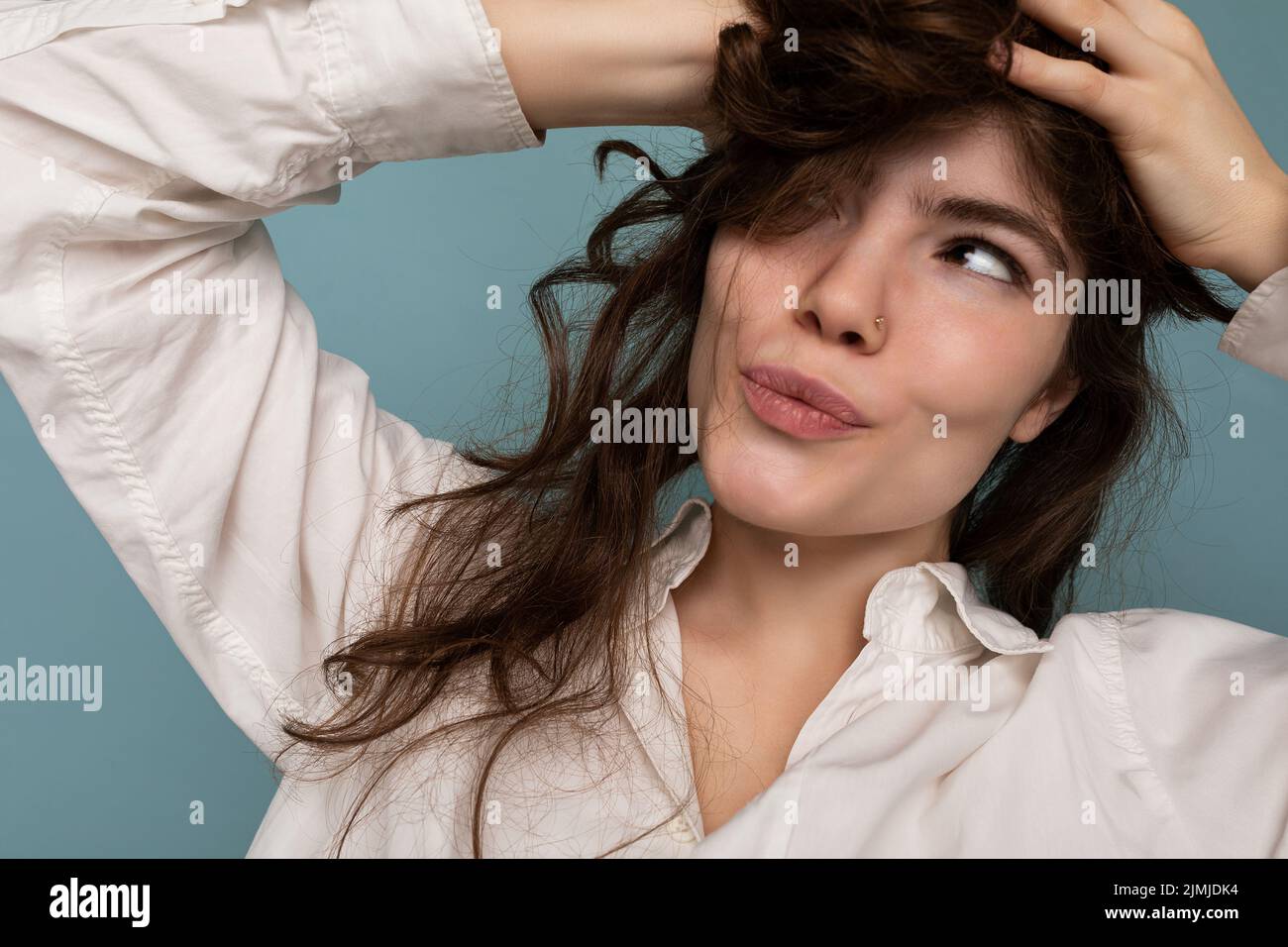 Closeup portrait of positive attractive crazy joyful funny young curly brunette woman isolated on blue background Stock Photo