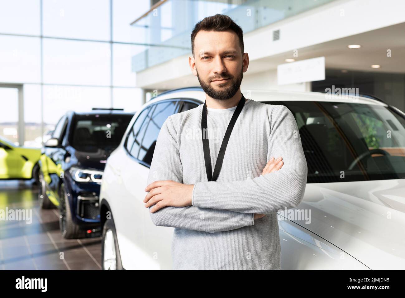Car dealership worker next to a new car looking at the camera with a smile Stock Photo