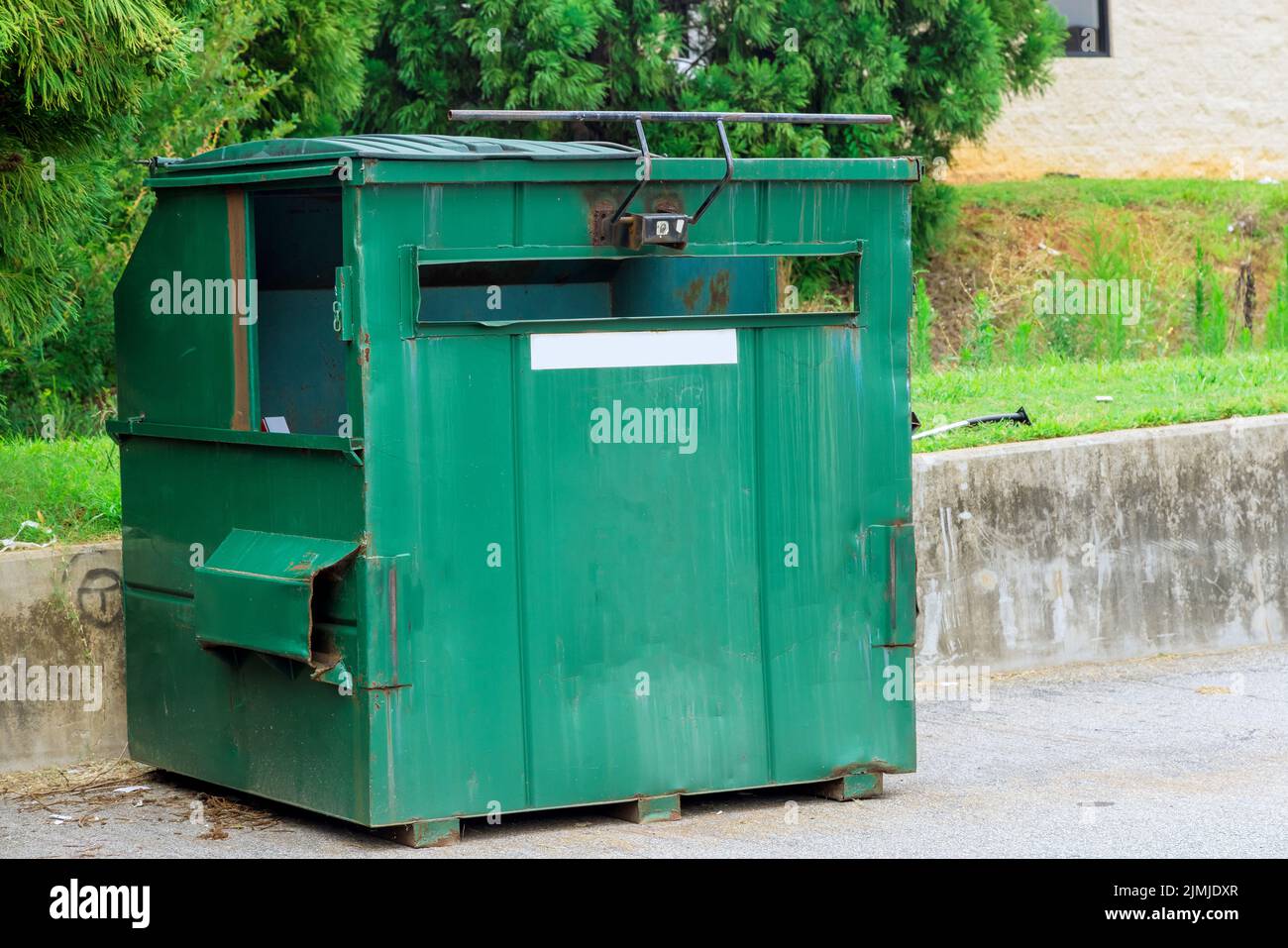 There is a garbage container bin near an apartment building where
