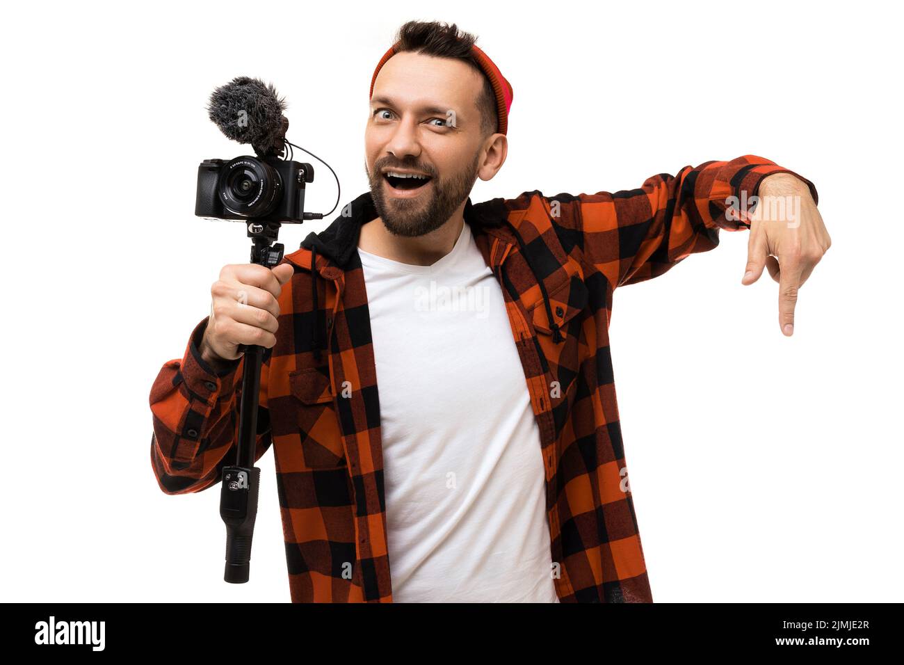 Bearded middle-aged man blogger with a camera and a microphone in his hands gesturing downwards on a white background Stock Photo