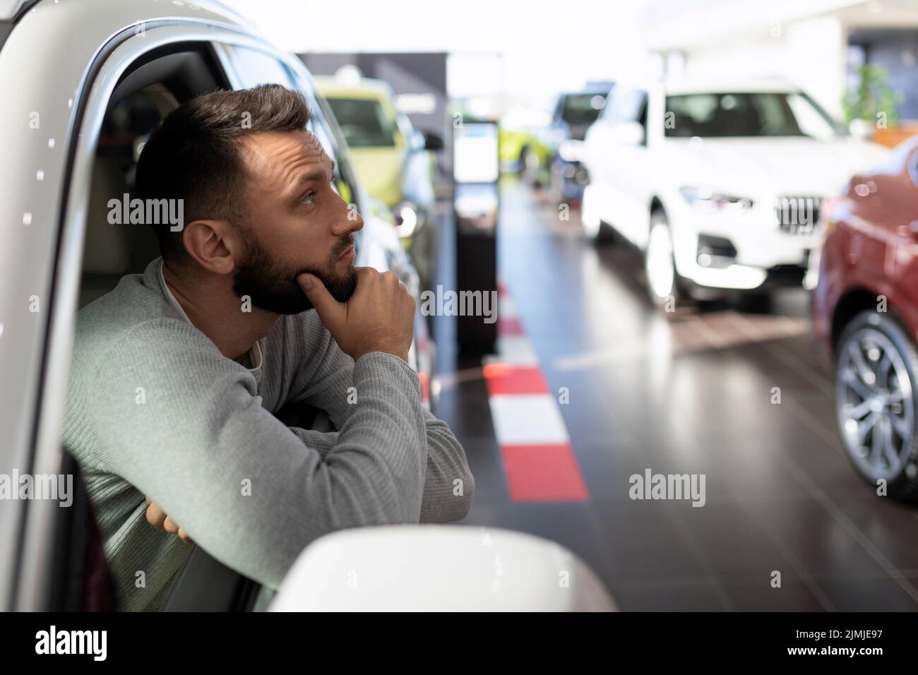 A man in a car dealership dreaming about buying a new car Stock Photo