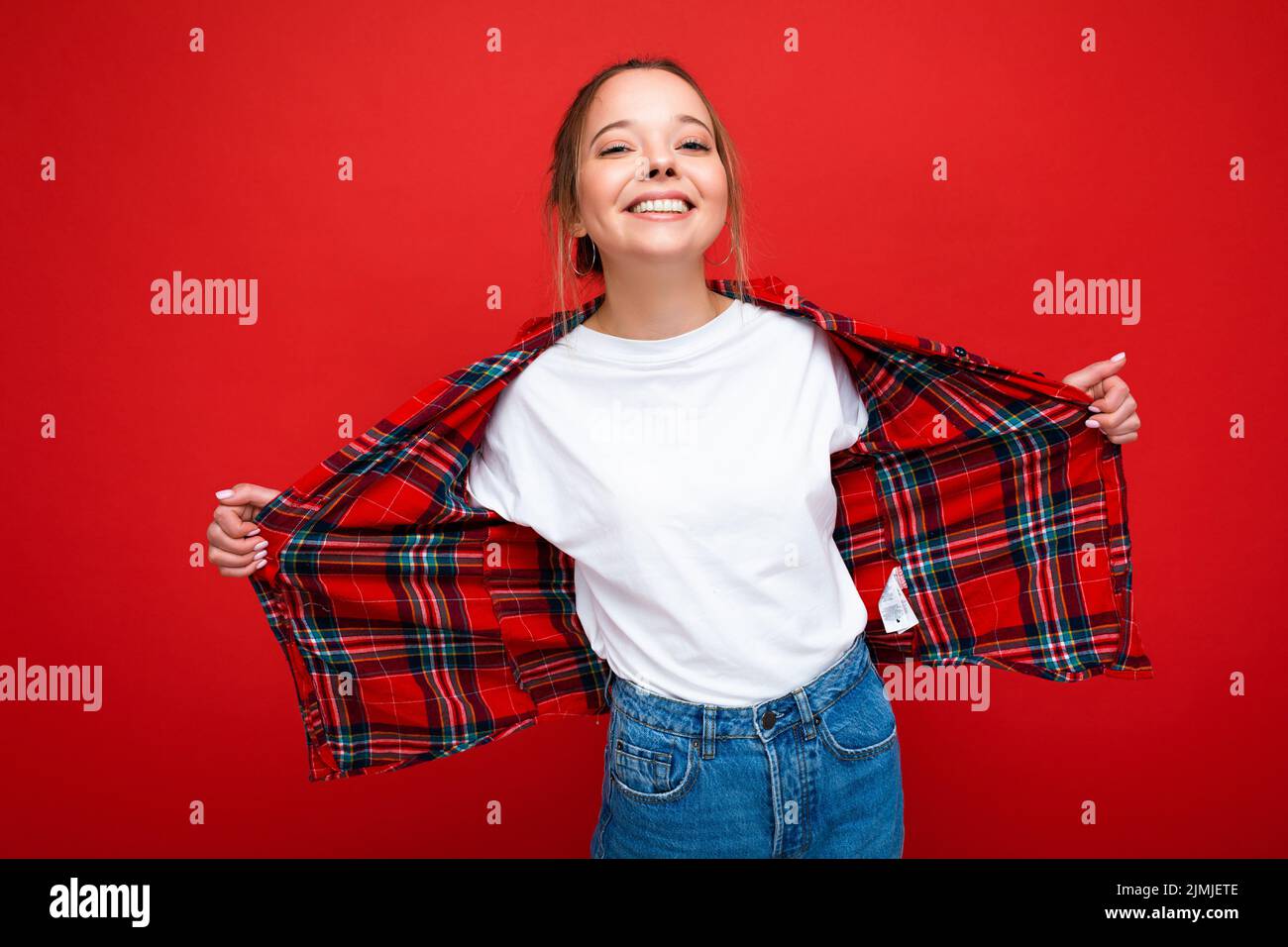 Young beautiful woman in stylish red hipster shirt and casual white t-shirt for mockup. Positive female shows facial emotions. F Stock Photo