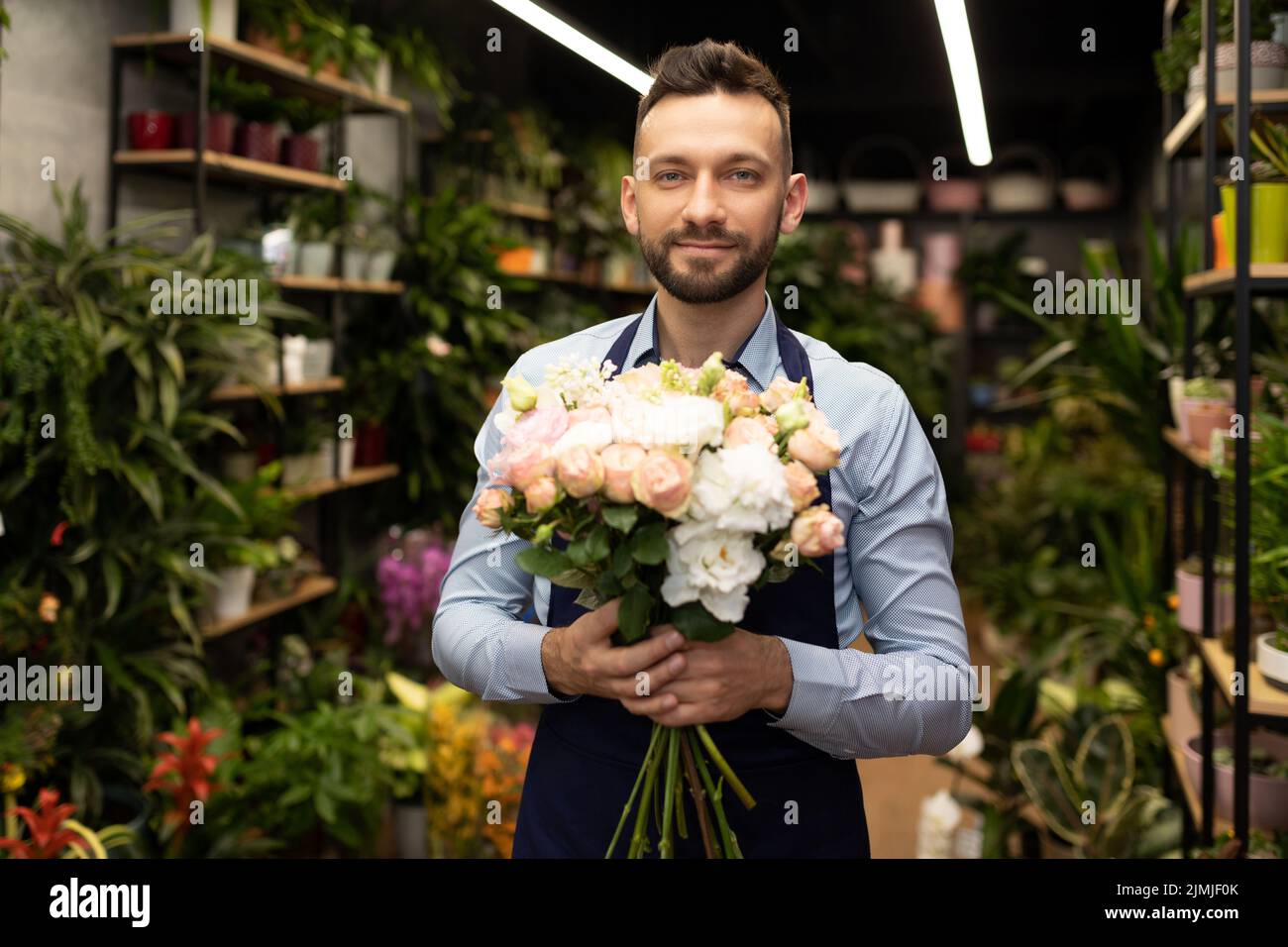 Businessman florist with a bouquet in his hands on the background of the flower shop Stock Photo