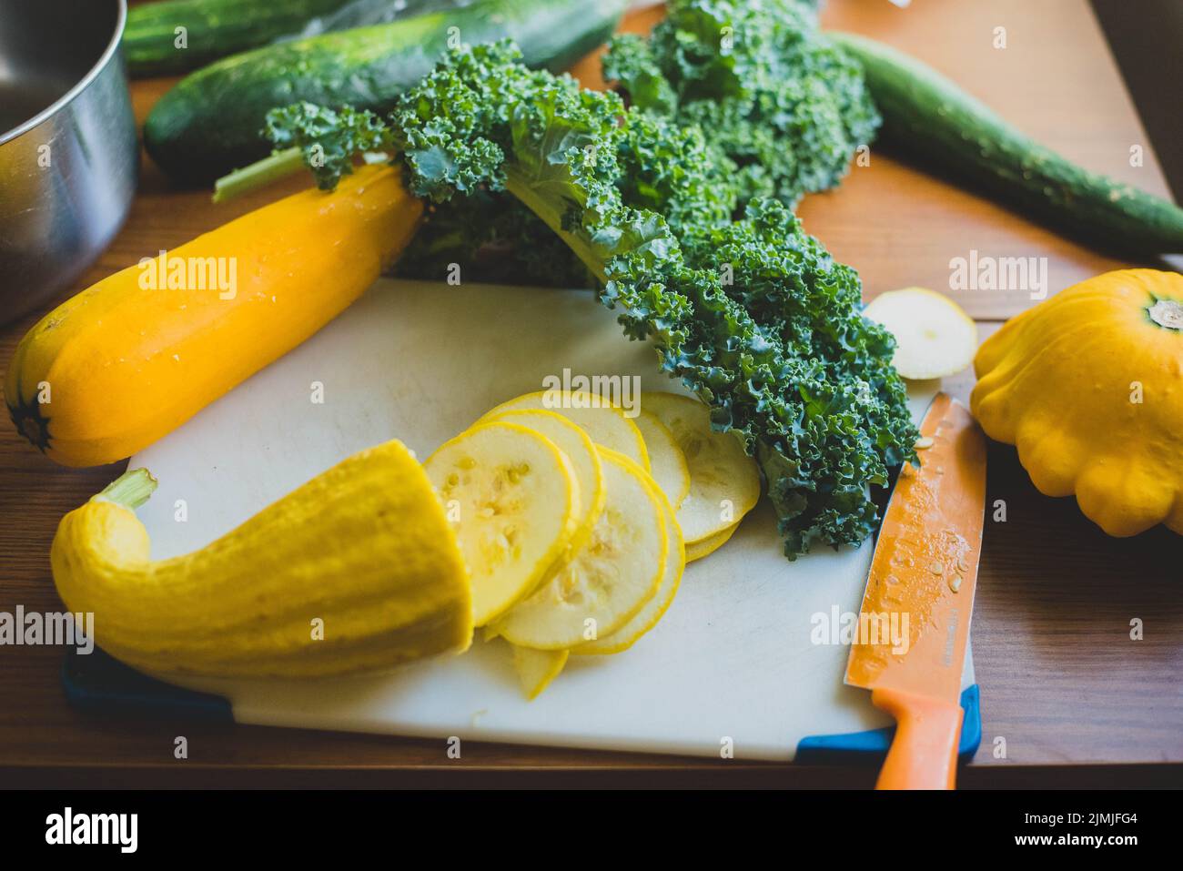 Squash and collard greens on a cutting board. - Stock Image