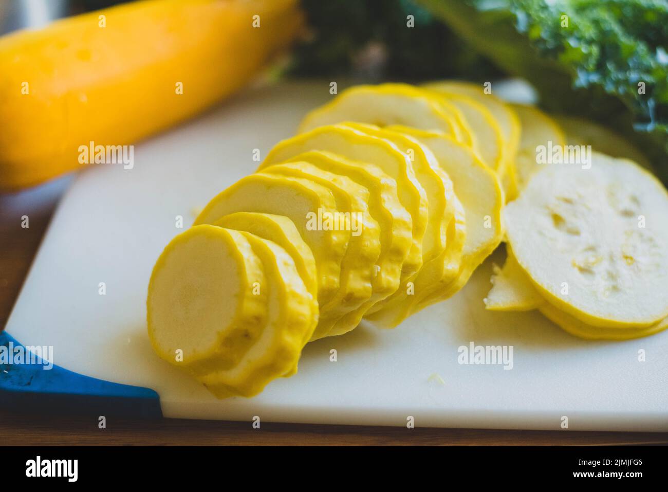 Squash and collard greens on a cutting board. - Stock Image
