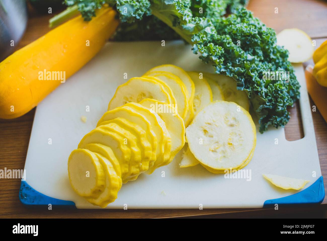 Squash and collard greens on a cutting board. - Stock Image
