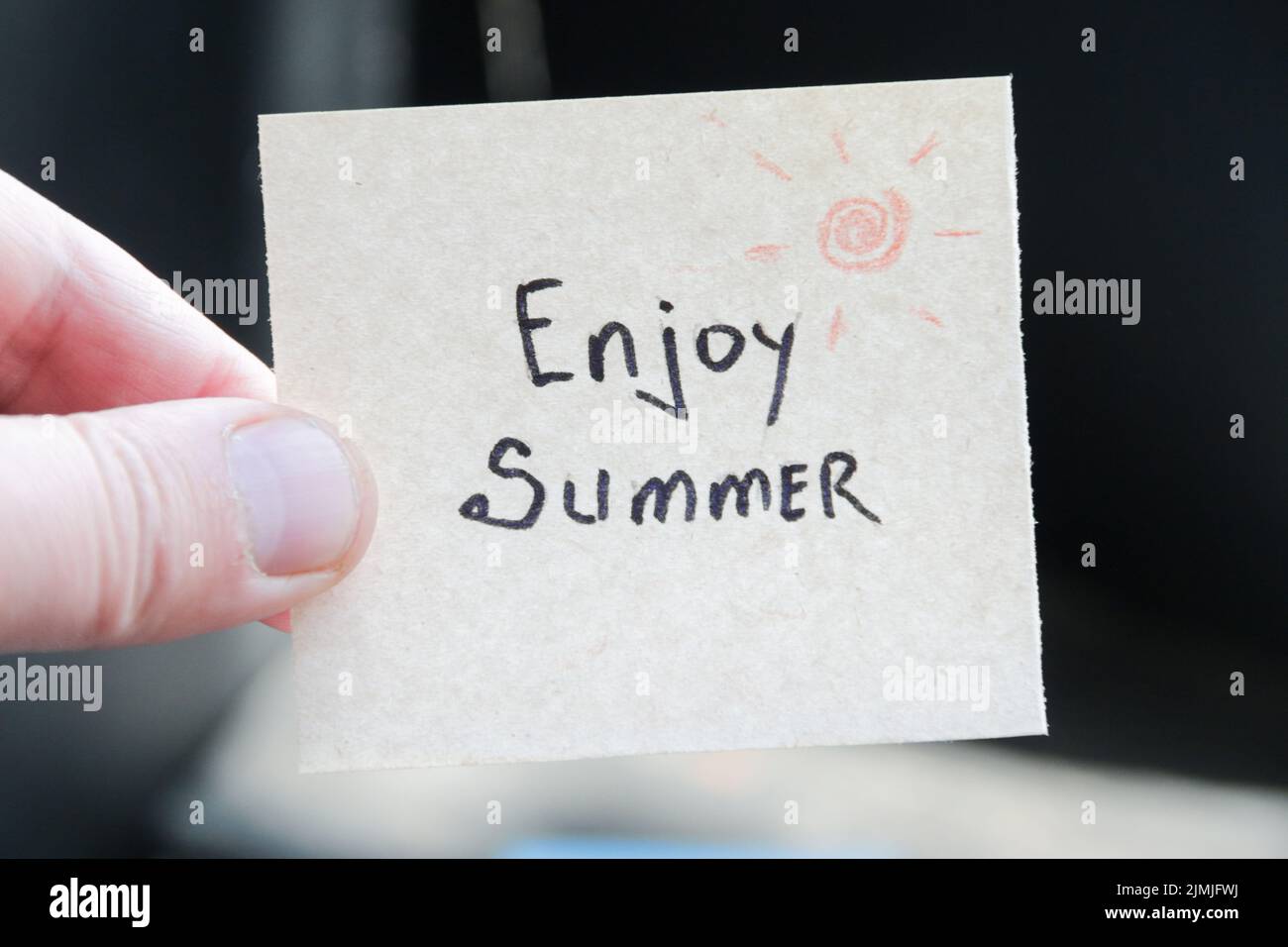 Enjoy summer. Creative concept. Hand holding a tag with the inscription. Stock Photo