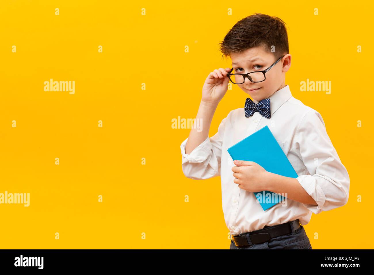 Young boy with glasses holding book Stock Photo