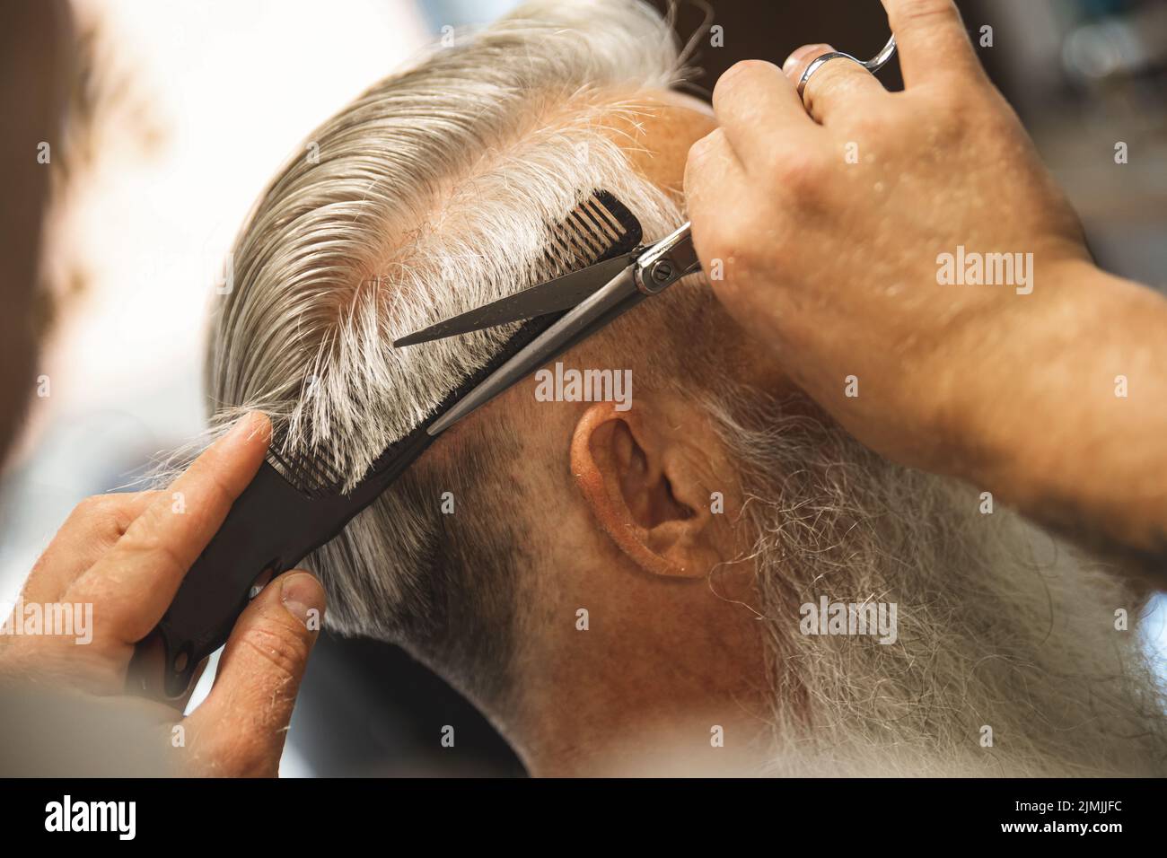 Hairdresser making stylish haircut for old man Stock Photo