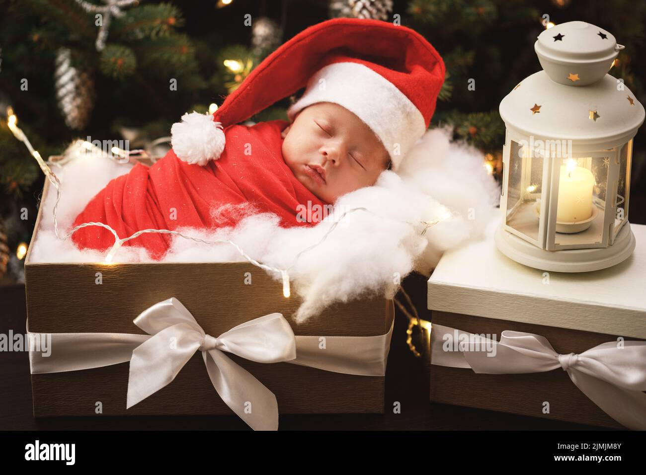 Cute newborn baby wearing Santa Claus hat is sleeping in the Christmas gift box Stock Photo